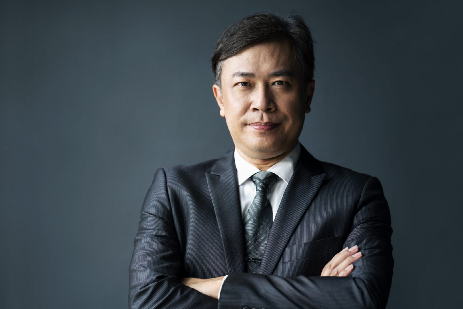 Confident man in business suit, arms crossed.
