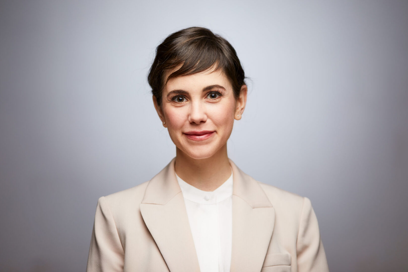Smiling person in a light-colored suit.