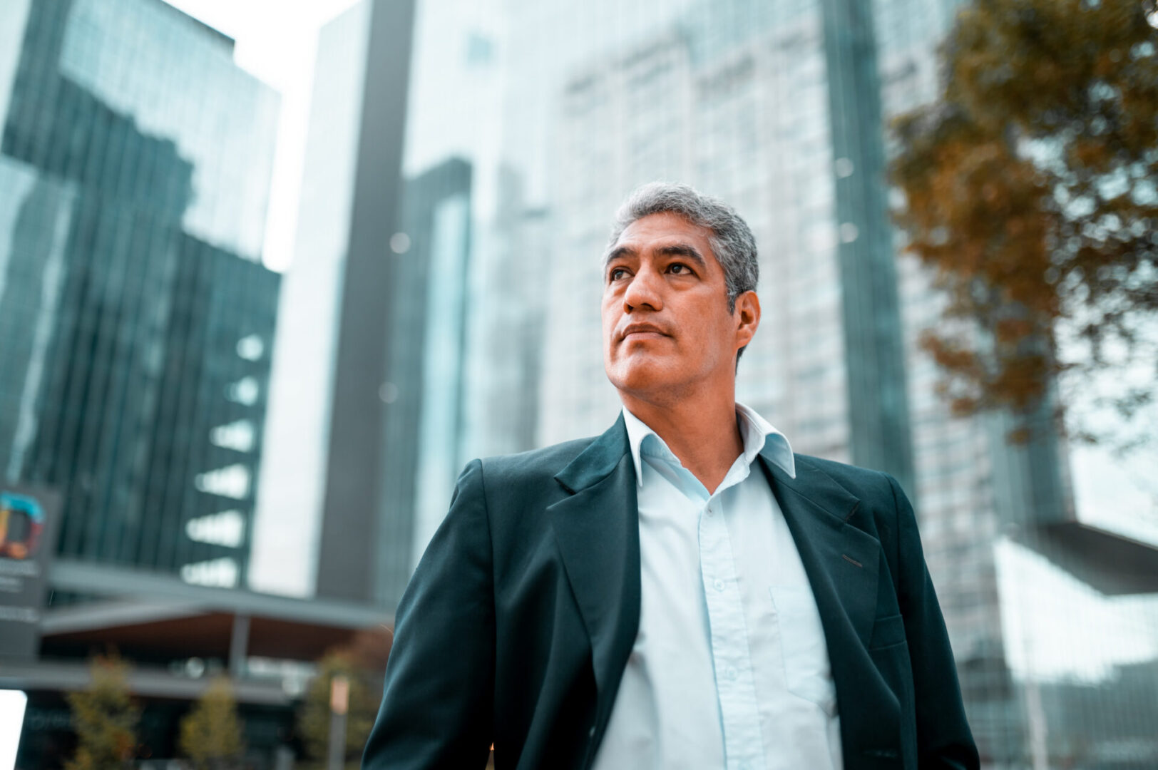 Man in suit standing among tall buildings.