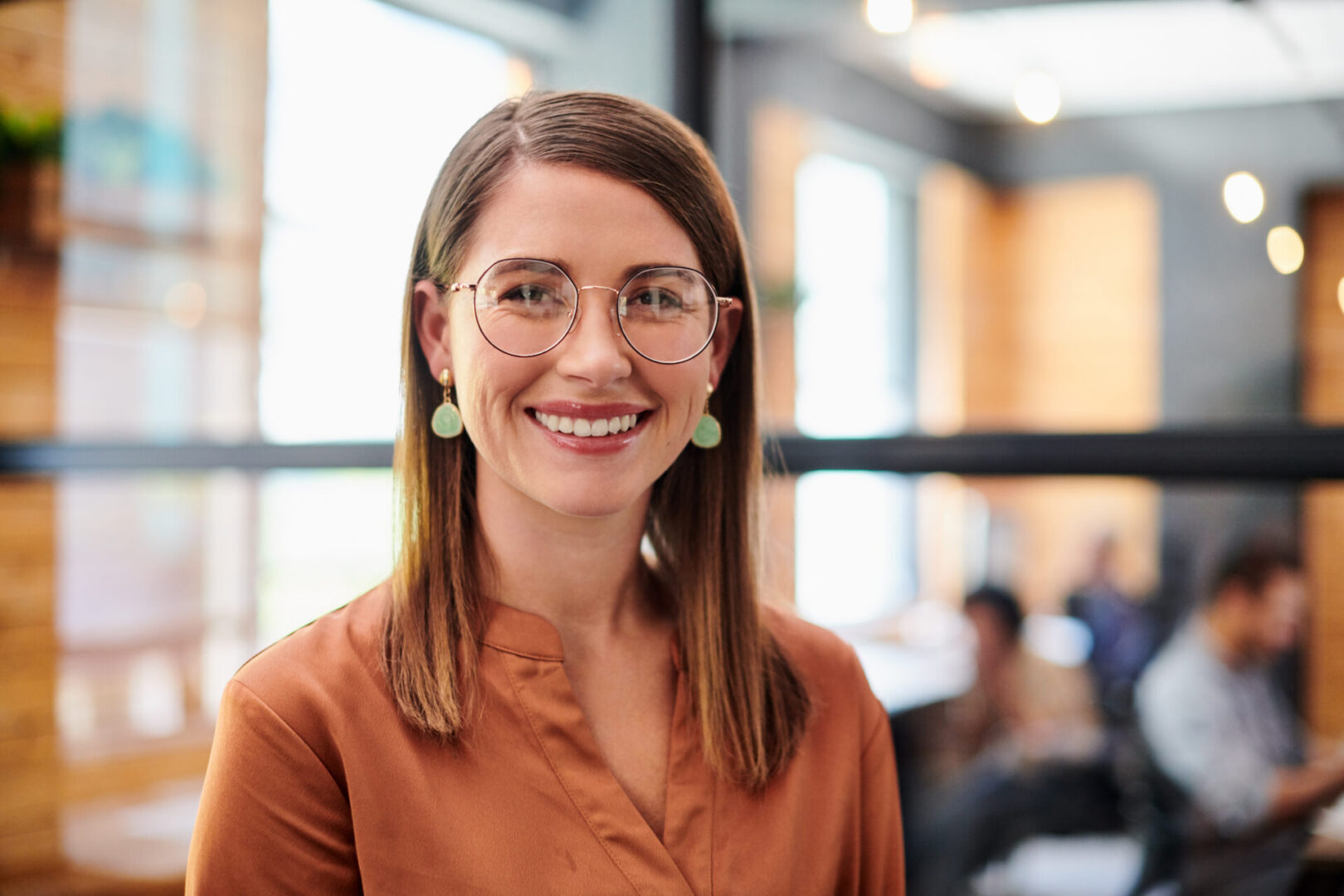 Smiling woman with glasses in office setting.