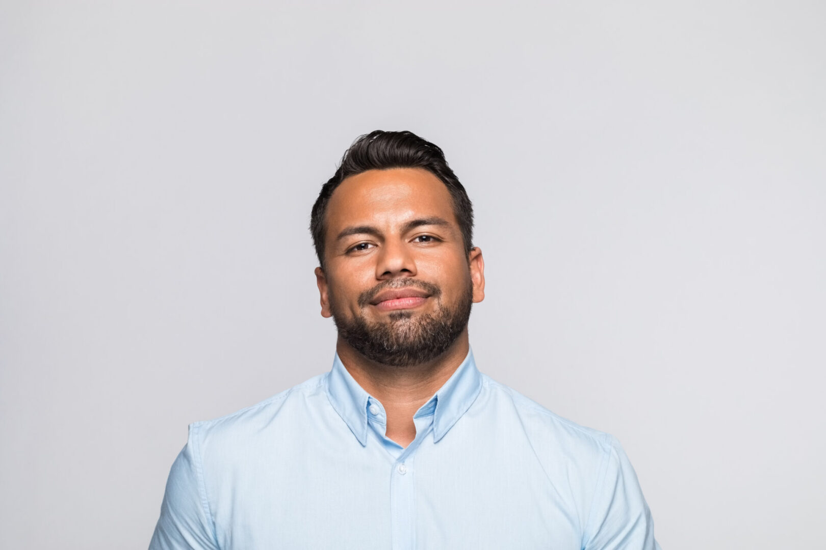 Man in blue shirt smiling confidently.
