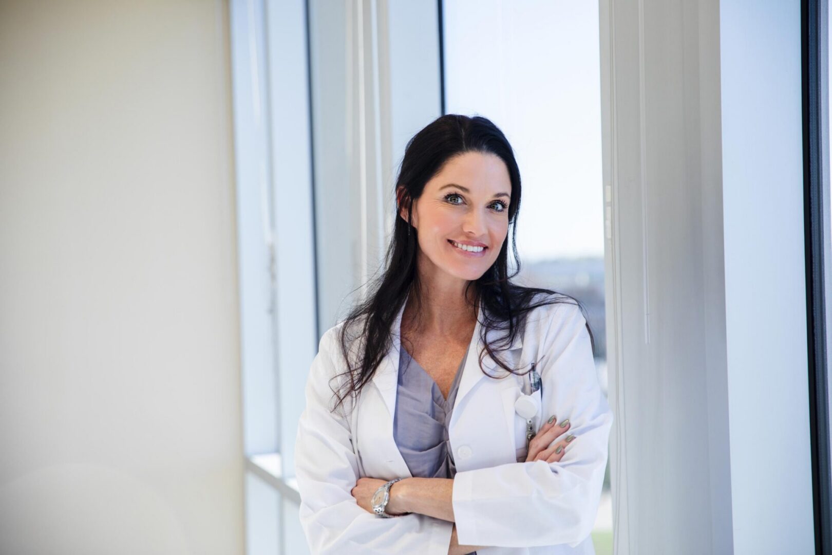 Smiling doctor in white coat by window.
