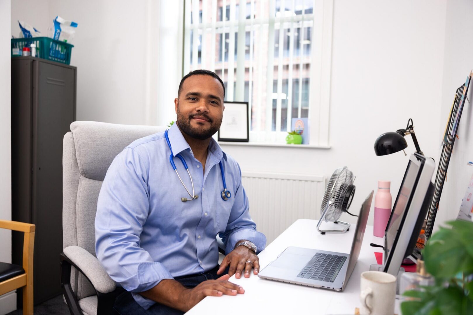 Doctor sitting at desk with laptop.