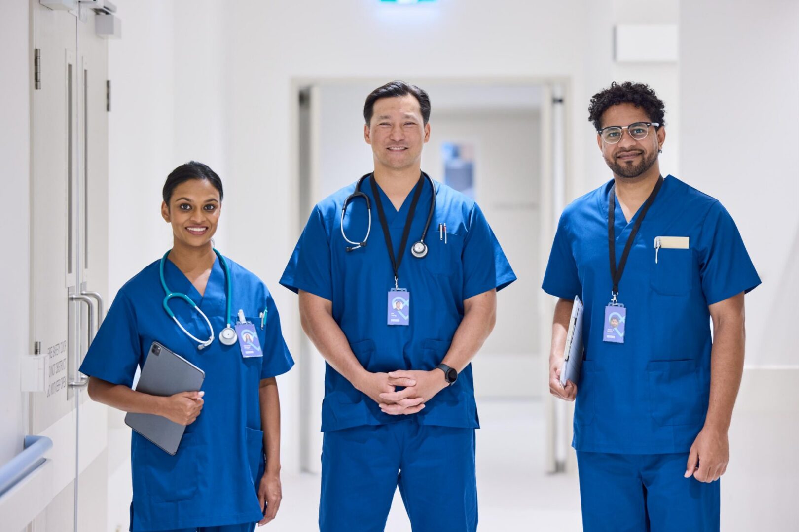 Three medical professionals in blue scrubs.